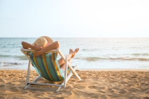 Kobieta w kapeluszu na leżaku, na plaży